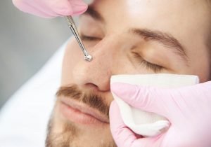 Extreme close-up of man nose during deep pore cleansing procedure with uno spoon